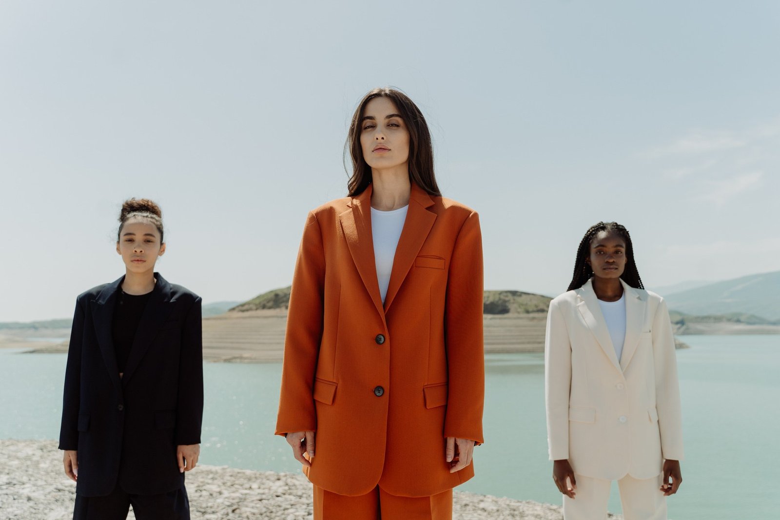 AUREA campaign — three figures by the water in rust, cream and ink